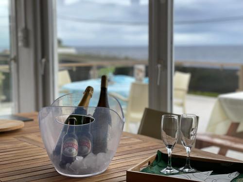a table with two wine bottles and two wine glasses at Carpe Diem Azores in Mosteiros