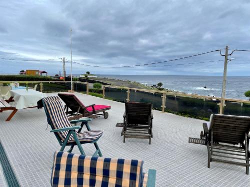 a patio with chairs and a table and the ocean at Carpe Diem Azores in Mosteiros