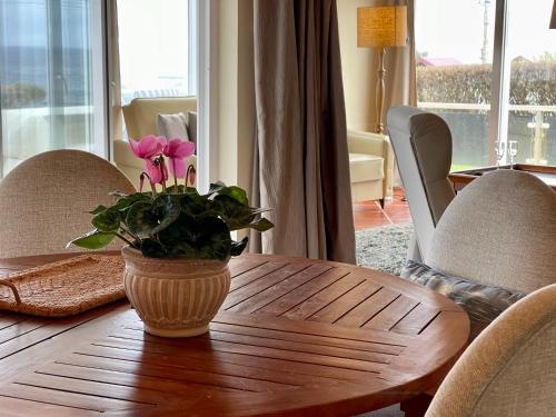 a wooden table with a vase with pink flowers on it at Carpe Diem Azores in Mosteiros