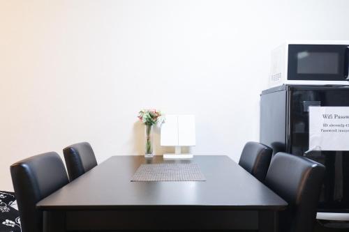 a dining room table with chairs and a microwave at Fukuoka Condominium in Fukuoka