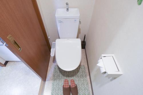 a bathroom with a toilet with two people standing next to it at Fukuoka Condominium in Fukuoka