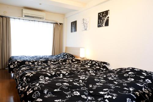 a bedroom with a black and white bed and a window at Fukuoka Condominium in Fukuoka