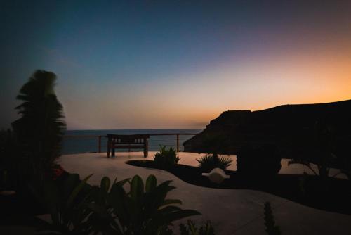 a sunset over the ocean with a bench on a beach at Etti - Paradise Suite La Gaviota in Pájara