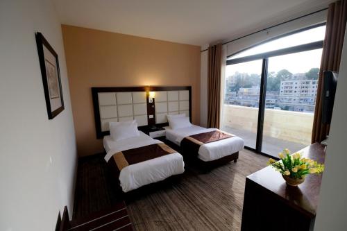 a hotel room with two beds and a large window at Ambassador City Hotel - Bethlehem in Bethlehem