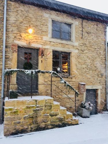 a stone building with snow on the stairs in front of it at Petite maison d'Amelotte in Sainte-Cécile