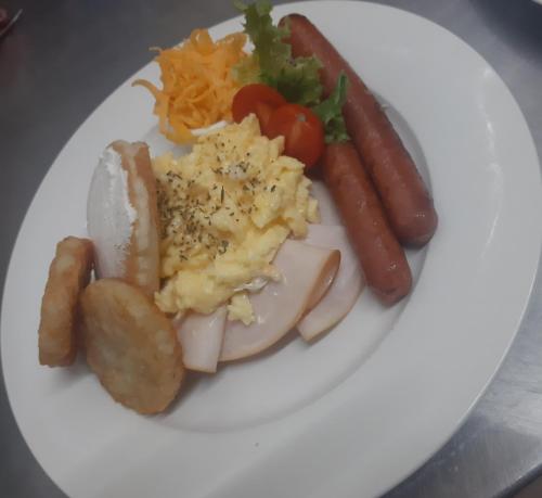 a white plate of food with sausage and vegetables at Acacia Gastehuis in Kathu