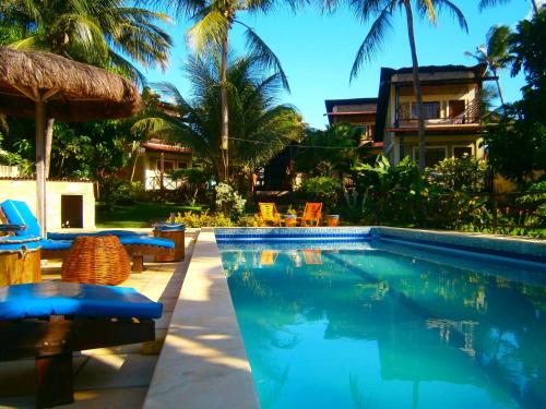 a swimming pool with chairs and a house at Pousada Vila Bacana in São Miguel do Gostoso