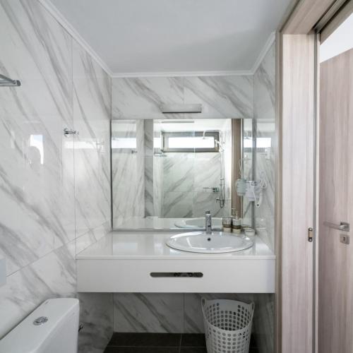 a white bathroom with a sink and a mirror at Agia Pelagia Villas in Agia Pelagia