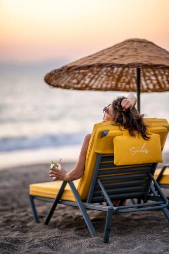 a woman sitting in a beach chair with an umbrella at Sundia Exclusive By Liberty Fethiye Adults Only in Fethiye