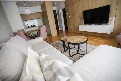 ein Wohnzimmer mit einem weißen Sofa und einem Tisch in der Unterkunft Bulevar Apartmani in Pale