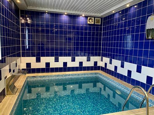 a bathroom with a swimming pool with blue and white tiles at Hotel Koral in Chernivtsi