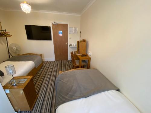 a hotel room with two beds and a tv at Four Seasons Guest House in Canterbury