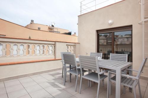eine Terrasse mit einem Tisch und Stühlen auf einem Gebäude in der Unterkunft APBCN Eixample Center in Barcelona
