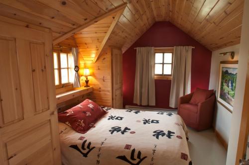 1 dormitorio en una cabaña de madera con 1 cama y 1 silla en Chalet Paradis de Charlevoix, en Baie-Saint-Paul