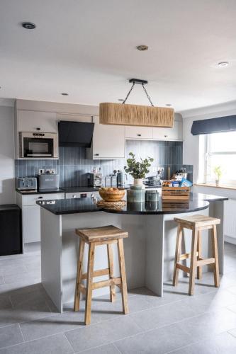 a kitchen with a large island with two wooden stools at The Kingswood Hotel in Sidmouth