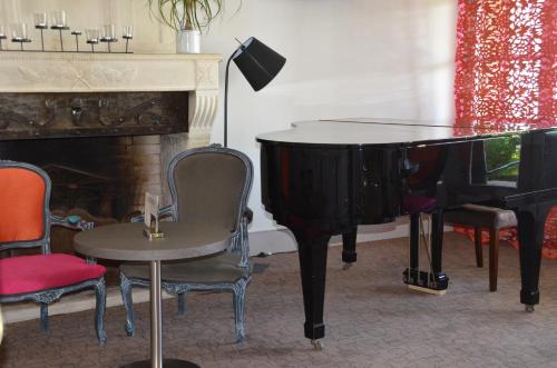 a room with a piano and a table and chairs at Hotel et Spa Les Cleunes Oléron in Saint-Trojan-les-Bains