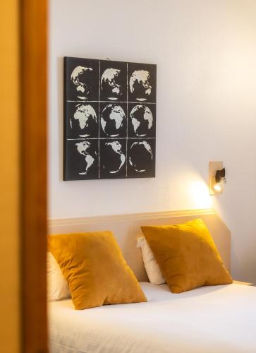 a bed with yellow pillows and a picture above it at Grand Hôtel Du Nord in Vesoul