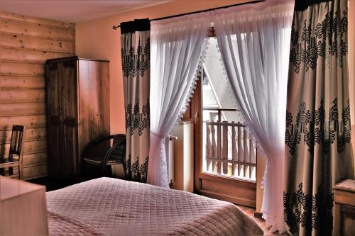 a bedroom with a bed and a window with curtains at Gościniec u Obrochtów in Zakopane