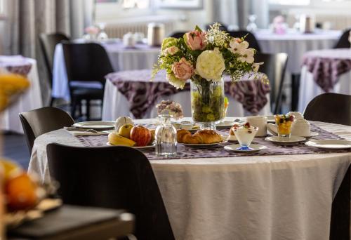 une table avec un vase de fleurs et des assiettes de nourriture dans l'établissement Grand Hôtel Du Nord, à Vesoul