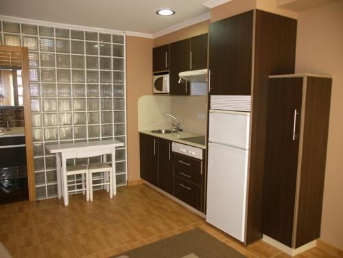 a kitchen with a white refrigerator and a table at Apartamentos Barrosa II in Portonovo