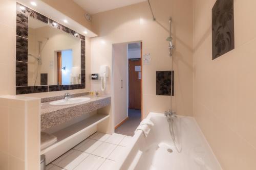 La salle de bains est pourvue d'une baignoire, d'un lavabo et d'une baignoire. dans l'établissement Grand Hôtel Du Nord, à Vesoul