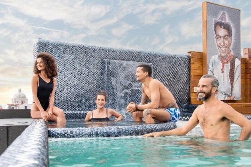 un groupe de personnes assises dans une piscine dans l'établissement L Hotel Perla Boutique, à Puebla