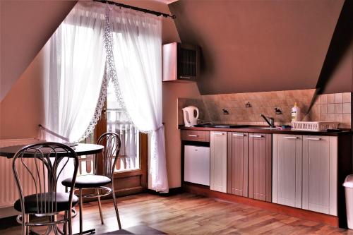 a kitchen with white cabinets and a table and a window at Gościniec u Obrochtów in Zakopane