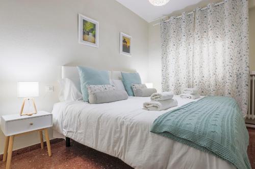 - une chambre avec un grand lit blanc aux accents bleus dans l'établissement Apartamentos Alameda del Tajo I Parquing Centro, à Ronda