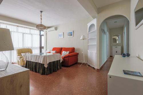 un salon avec une chaise rouge et une table dans l'établissement Apartamentos Alameda del Tajo I Parquing Centro, à Ronda