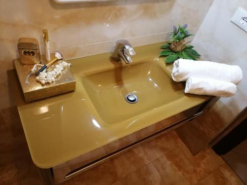 a yellow sink in a bathroom with towels on it at Hotel Riposo in Gatteo a Mare