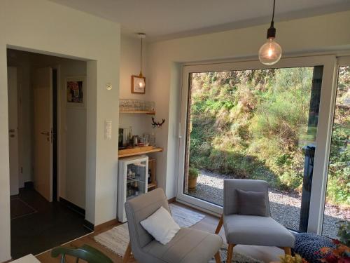 a living room with two chairs and a large window at B&B Les Lits de Nohaipré in Rendeux