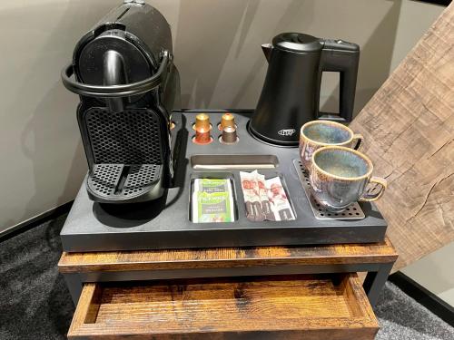 a table with a coffee maker and cups on it at Hotel de Prince in Nijmegen