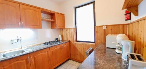 a kitchen with wooden cabinets and a sink and a window at Varga Gardens Balatonmáriafürdő in Balatonmáriafürdő