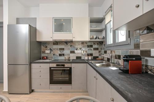a kitchen with white cabinets and a stainless steel refrigerator at LA CASA DE LA VIDA in Naxos Chora