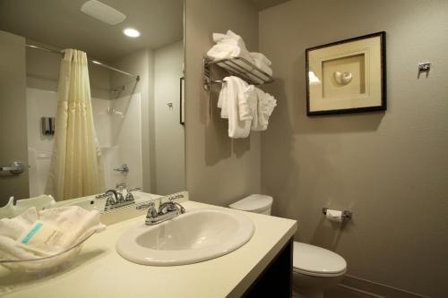 uma casa de banho com um lavatório, um WC e um espelho. em River Inn at Seaside em Seaside