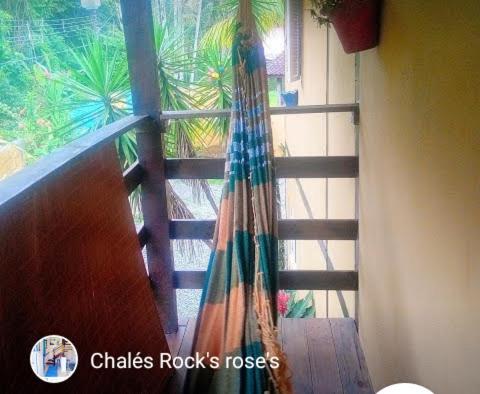 a balcony with a hammock in front of a window at SUITES E CHALES PRIVADOS Rock's&Rose's home in Camburi