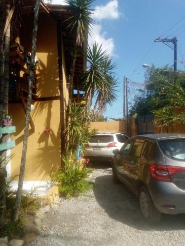 two cars parked next to a building with palm trees at SUITES E CHALES PRIVADOS Rock's&Rose's home in Camburi