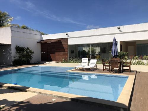 a swimming pool with chairs and a table and an umbrella at Terra Bahia in Aracaju