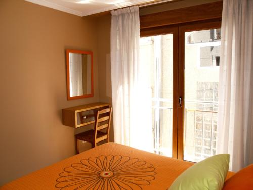 a bedroom with a bed and a large window at Apartamentos Barrosa II in Portonovo