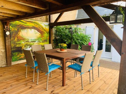 une table et des chaises en bois sur une terrasse avec un tableau dans l'établissement Les Tourterelles, à Vendôme