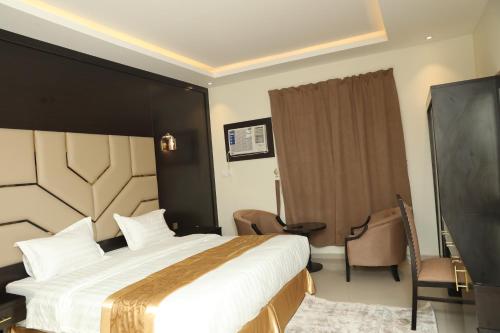 a hotel room with a large bed and a chair at شقق السامية للشقق المخدومة in Sharurah
