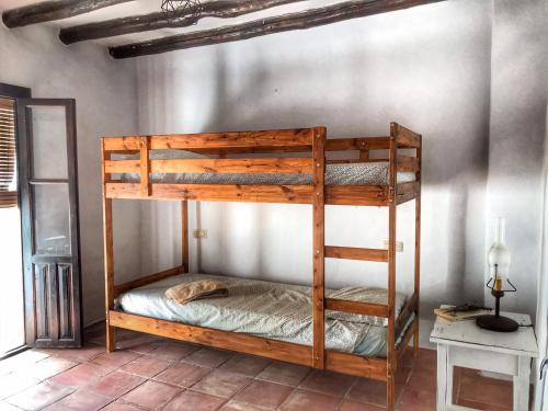 Litera de madera en una habitación con pared en Casa Juncaria, en Yunquera
