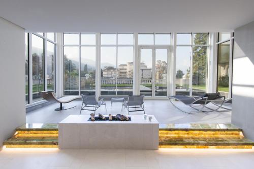 a living room with a fireplace and chairs and windows at Grand Hotel des Iles Borromées & SPA in Stresa