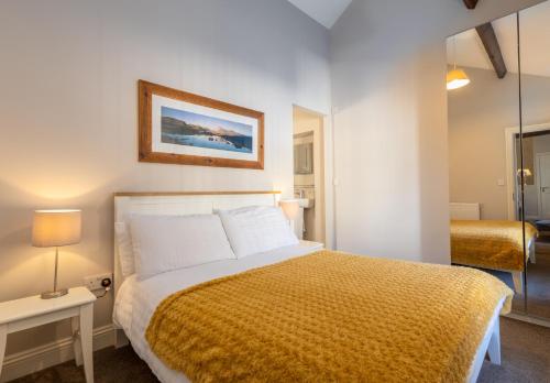 a bedroom with a large bed with a yellow blanket at Brampton Holiday Homes - The Mews Apartment in Brampton