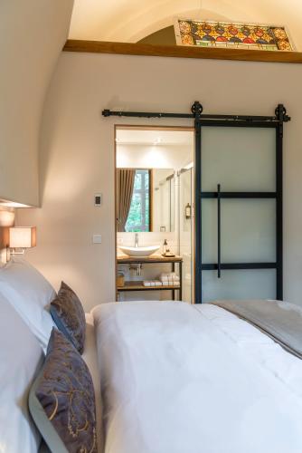 a bedroom with a bed and a bathroom with a sink at KerkHotel Biervliet in Biervliet