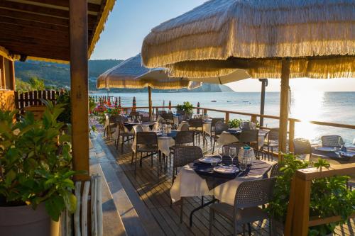 un restaurant avec des tables et des parasols sur la plage dans l'établissement Ferienwohnung ulivo mit Pool und Privatstrand, à Mattinata