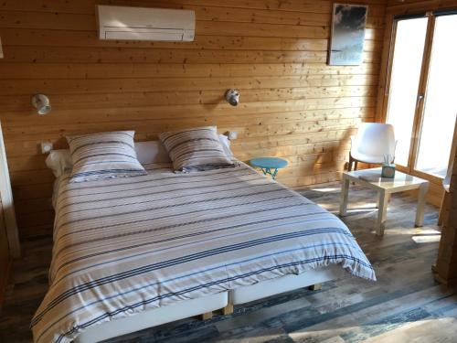 Bett in einem Zimmer mit einer Holzwand in der Unterkunft Chalet de La Source in Rognac