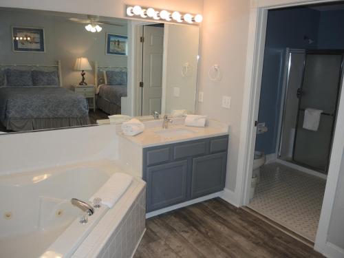 a bathroom with a tub and a sink and a mirror at Studio Style Home 308L features Golf in Calabash