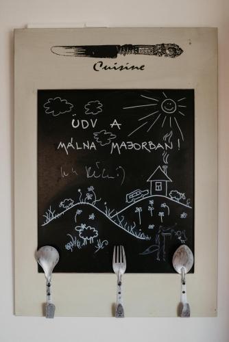 a chalkboard with a drawing on a wall with two forks at Málna Major in Mályinka