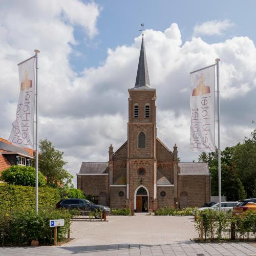 a church with two flags in front of it at KerkHotel Biervliet in Biervliet